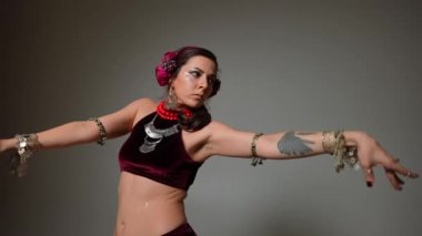 Kendine güvenen dansçının orta ölçekli portresi kameraya bakıyor yavaş çekimde elleri hareket ettiriyor ve yana bakıyor. Kafkasyalı yetişkin kadın gri arka planda gösteri yapıyor.