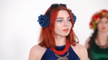 Kendine güvenen güzel bir kadın ağır çekimde göğsünü sallayarak göbek dansı yapıyor. Beyaz arka planda beyaz dansçı ve arka planda bulanık bir kadın olan çekici kızıl saçlı beyaz dansçı portresi.