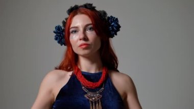 Kendine güvenen dansçının portresi gri arka planda ağır çekimde oynuyor. Genç, zayıf, beyaz kadın ciddi bir yüz ifadesiyle Orta Doğu dansı yapıyor.