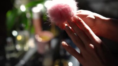 Üst düzey kadın eli pembe yüzüğü parmağına takıyor ve pofuduk topu sallıyor. Tanınamayacak kadar zayıf, kendine güvenen genç bir kadın güneşli bir günde evde hazırlanıyor.