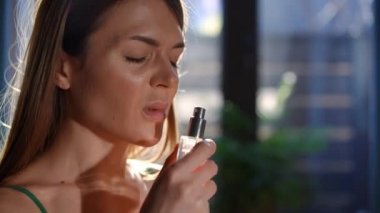 Yakından memnun olmayan genç bir kadın parfüm kokusu alıyor mide bulandırıcı bir yüz ifadesiyle burnunu kapatıyor. Soldaki ince, güzel, beyaz kadın hoş olmayan parfümlü, kapalı bir yerde.