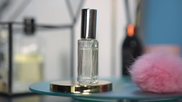 特写古龙水瓶和粉色蓬松球旋转缓慢的玻璃托盘 室内香水和装饰 — 图库视频影像