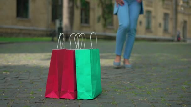 优雅的 无法辨认的女人的腿在户外漫步 走过购物袋 慢吞吞地离去 白种人成功的富婆走在城市里 在地上买东西 — 图库视频影像