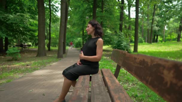 공원에서 임산부가 벤치에 야외에서 휴식을 취하는 스러운 — 비디오