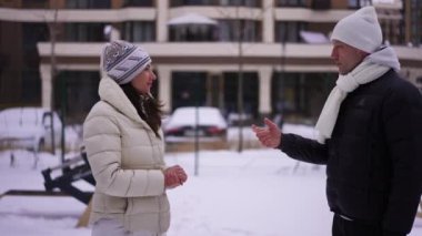 Olumlu yetişkin sporcu ve sporcu kış günü spor sahasında el kol hareketi yapan bir kadın. Kenar görüşlü, kendine güvenen beyaz bir çift açık havada antrenman yapıyor.