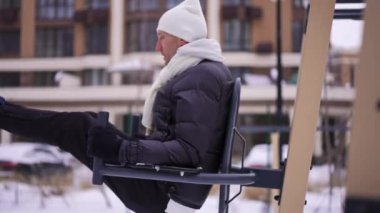 Kenar görüşlü, formda bir adam spor sahasında çalışıyor. Kış günü egzersiz yapan kendinden emin Kafkas sporcusu