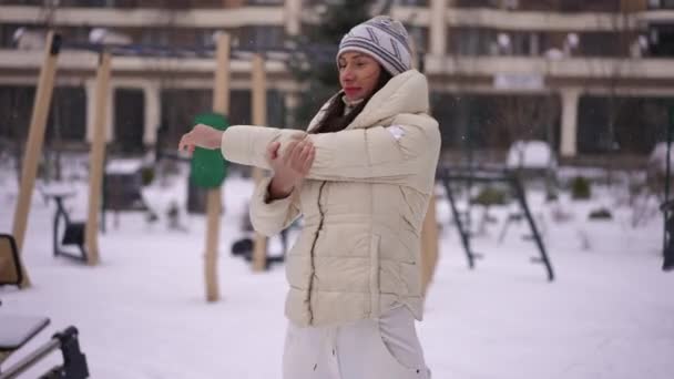 雪の冬の屋外で暖まる白人の笑顔のスポーツ女性をフィットさせます 中出しポルノの確信若いです美しいですスリム女性ストレッチ筋肉トレーニングワークアウト — ストック動画