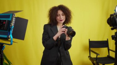 Çekici gülümseyen blogcu sarı arka planda video blogu kaydeden yeni bir kamera eleştirisi yapıyor. Beyaz, kendine güveni tam genç bir kadının portresi.
