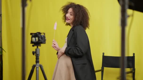Szczęśliwa Ciężarna Vlogger Mówi Stojąc Papierowym Smoczkiem Dla Dzieci Żółtym — Wideo stockowe