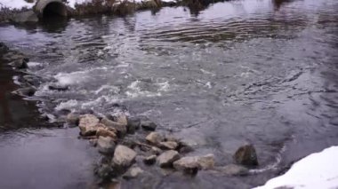 Close-up rocks with clean cold water flowing outdoors on cloudy spring autumn day. River stream in mountains with no people