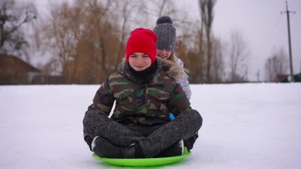 Relaxed Teen Boy Sitting Green Sled Girl Pushing Friend Leaving — Stock Video