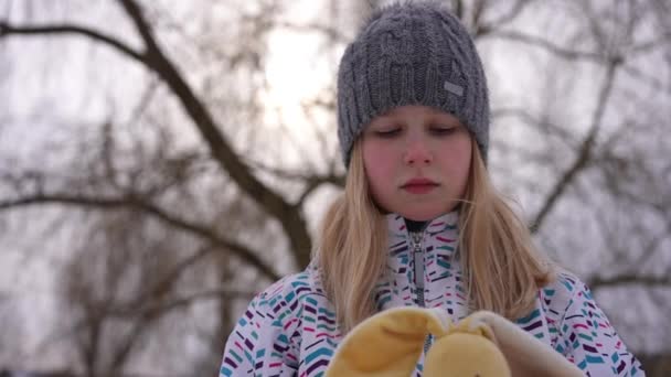 落ち込んでいる10代の少女のポートレート動揺顔の表情でカメラを見ておもちゃを抱擁 欲求不満な白人ティーンPosingでスローモーション屋外で曇り冬の日 — ストック動画