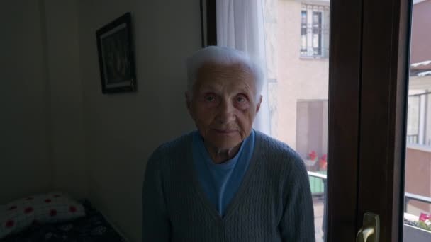白种人老妇人 灰白的头发站在室内 望着远方 家中黑暗中迷人的退休女性的画像 — 图库视频影像