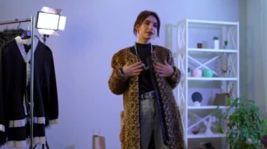 Slim gorgeous woman trying on leopard print fur coat in slow motion looking at camera and looking away. Portrait of confident Caucasian attractive millennial lady getting ready choosing outfit