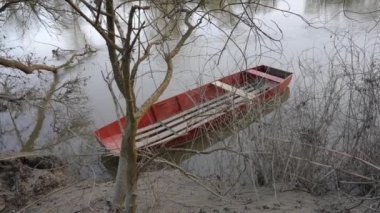 Gri suyu açık havada bulutlu bir günde akan tahta bir tekne. İlkbahar Gölü 'ndeki küçük su aracının yüksek açılı görüntüsü