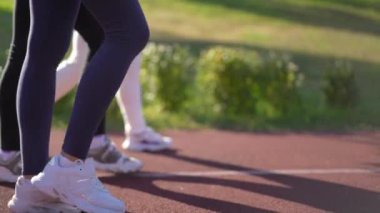 Kırmızı spor pistinde yürüyen sporcu kadınların bacakları sağa sola doğru dönen canlı kamera gibi. Güneşli bahar günlerinde dışarıda antrenman yapan tanınmayan kendine güvenen kadınlar. Yavaş çekim