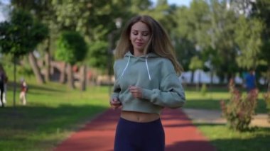 Güneş ışığında ağır çekimde koşan güzel, zayıf, beyaz bir kadın. Güneşli bir günde açık havada koşuya çıkan kendinden emin güzel bir sporcunun Dolly portresi.