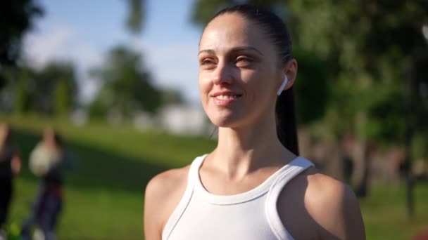 Uśmiechnięta Pewna Siebie Sportowiec Słuchawkach Uśmiecha Się Odwracając Wzrok Aparatu — Wideo stockowe