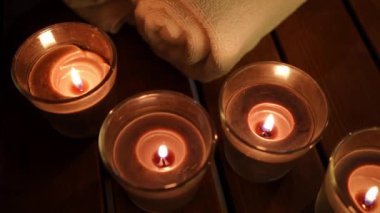Üst tarafta, karanlıkta yanan mumlar, tahta bankta beyaz havlular. SPA salonundaki dekorasyonda hiç insan yok.