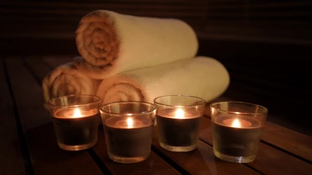 用舒适的深色美感Spa把装饰蜡烛和卷起的毛巾包好 室内黑暗中燃烧的特写装饰 — 图库视频影像