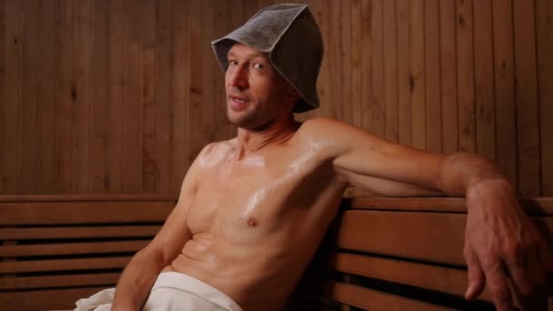 Retrato Homem Transpirando Sentado Sauna Quente Olhando Para Câmera Gesticulando — Vídeo de Stock