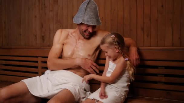 Wesoły Biały Ojciec Łaskocze Córkę Śmiejąc Się Siedząc Drewnianej Saunie — Wideo stockowe