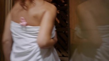Finn saunasına bir erkek ve bir bayanla giren tanınmamış bir kadın. Beyaz bir aile, SPA 'nın sıcak ahşap odasıyla evden çıkıyor.