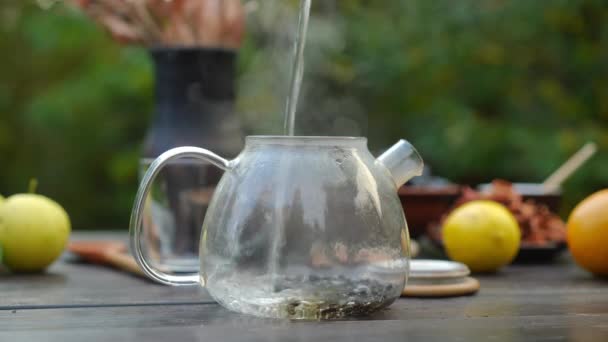 透明なガラス容器にお湯を注ぐと閉じティーポット 秋の日は屋外でお茶を淹れるのをやめましょう — ストック動画