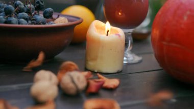 Yakın plan kurumuş meyveler açık havada yanan mumlarla masaya düşüyor. Sonbahar günü lezzetli, sağlıklı organik yiyecekler. Sağlık ve vitamin konsepti