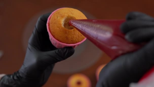 特写顶部视图挤压红色果酱孔松饼室内 雌性手戴手套 用美味的橘子酱填满美味的糕点 烘焙和烹调概念 — 图库视频影像