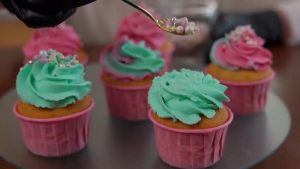 特写可食用珍珠洒在茶杯蛋糕上 绿色玫瑰结冰在盘子里 一个不知名的女人在家里的面包店里装饰美味的烘焙糕点 小企业和生活方式 — 图库视频影像