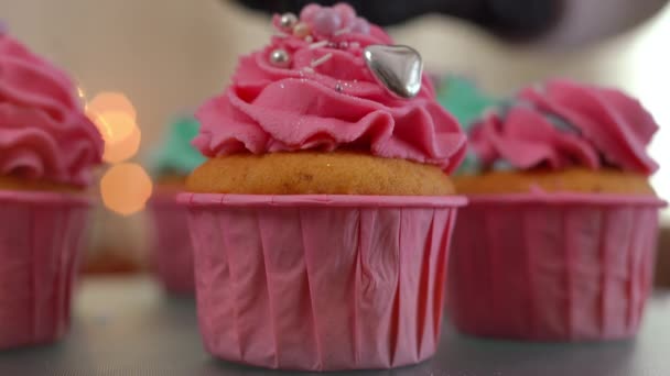 极度特写美味的纸杯蛋糕与粉红色皇家糖衣和室内可食珍珠 在烤松饼特写上洒上美味的配料 — 图库视频影像
