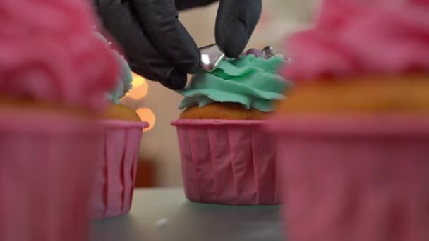 手拿着可食用珍珠放在烤松饼纺盘上 前面有模糊的纸杯蛋糕经过相机 无法辨认的糖果店在室内烘焙美味的甜点 — 图库视频影像