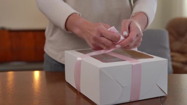 Неузнаваемая Женщина Завязывающая Розовую Ленту Бумажной Коробке Вкусной Выпечкой Продажу — стоковое видео