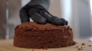 Masanın üzerinde sicim olan iki parça çikolatalı pasta kalıbını ayıran yakın çekim. Eldivenli tanınmayan bir kadın mutfaktaki lezzetli pastaları kesiyor.