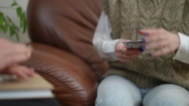 Kapalı mekandaki randevusu için terapiste para ödeyen tanınmayan genç hastalara yakın çekim. Kadın eli nakit para uzatıyor.