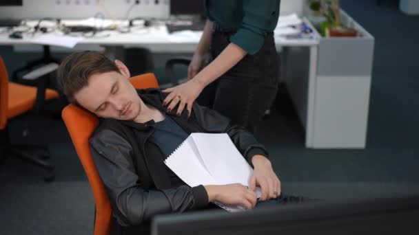 无法辨认的女人从睡在办公椅上的同事身边醒来 工作过度劳累的白人年轻人在工作时在室内小睡的画像 — 图库视频影像