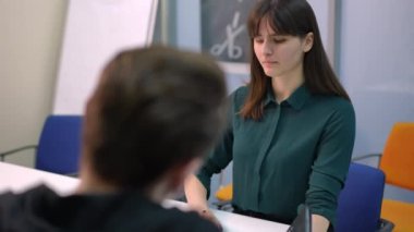 Ciddi bir bayan yönetici, masada oturan çalışanların konuşmalarını dinliyor. Ofiste iş arkadaşlarıyla proje planlayan kendinden emin beyaz bir kadının portresi.