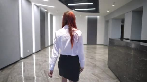ライブカメラは若い女性がオフィスのロビーにエレベーターに歩いて入るガラスのドアを通過します 朝の白人女性従業員の追跡ショット ウクライナ語でマスクの禁止記号なしの入り口 — ストック動画