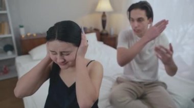 Yüksek açılı, ağlayan genç bir kadın elleriyle kulaklarını kapatıyor kızgın öfkeli bir adam yatak odasından çıkarken bağırıyor. Çaresiz, stresli, beyaz bir kadının evde kocasıyla tartışan portresi.