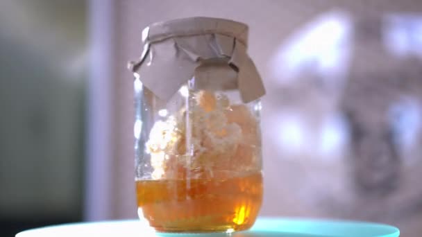 蜂蜜和香甜液体琥珀蜂蜜在瓶子里旋转室内 在阳光下把美味的健康食品放在罐子里 — 图库视频影像