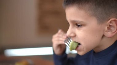 Kafkasyalı bir çocuğun yavaşça çiğneyen hamur köftelerinin kafasından görünüşü gülümseyerek. Kafede yemek yiyen çocuğun yakın plan portresi.