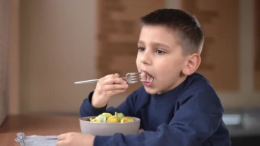 Kahverengi gözlü esmer çocuğun portresi kafede lezzetli hamur tatlısı yiyor. Kafkasyalı çocuk tatmin olmuş yüz ifadesiyle lezzetli bir akşam yemeğinin tadını çıkarıyor.