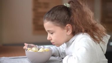 Kafedeki masada oturmuş gülümseyen lezzetli börekler kokan güzel beyaz kız. İçerde yemek yiyen pozitif, rahat çocuk portresi.