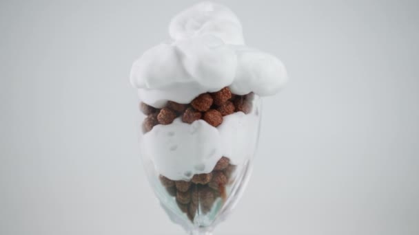 ホイップクリームをトッピングしたチョコレートボールのグラスを閉じます 白を基調にした美味しい甘いデザートが近くにあります スローモーション — ストック動画