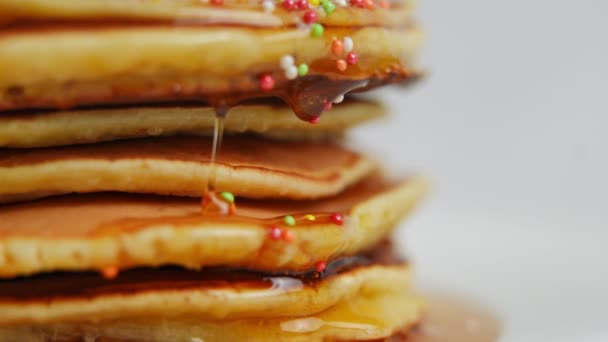 特写蜂蜜滴与五彩缤纷的糖球流下一堆奶油 美味可口的甜食 配以白底配餐 — 图库视频影像