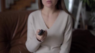 Uzaktan kumandadan mutlu, beyaz, hamile bir kadının ilginç bir gülümseme filmine odaklan. Heyecanlı beklentiler evde oturup televizyon izlemenin keyfini çıkarıyor.