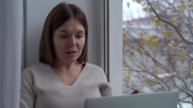 Pencereden dışarı bakan hamile bir kadının e-posta gönderme portresi. Mutlu kendinden emin Kafkas beklentisi evde pencere eşiğinde oturuyor.