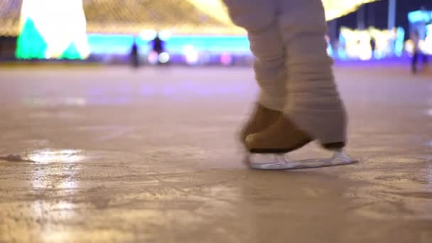 冬の夜に屋外でゆっくりと動き回るアイススケートのクローズアップ女性の足 誰もが認めるプロの女性トレーニングスケートオンアイスリンクアップ — ストック動画