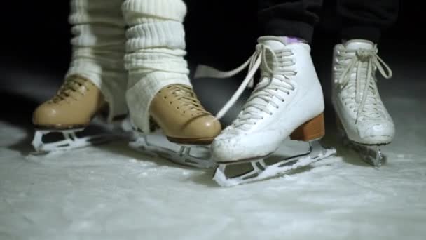暗闇の中で白い雪の上に氷のスケートでクローズアップ女性の足 2人の無名の女性が屋外で趣味を楽しんでスケート — ストック動画